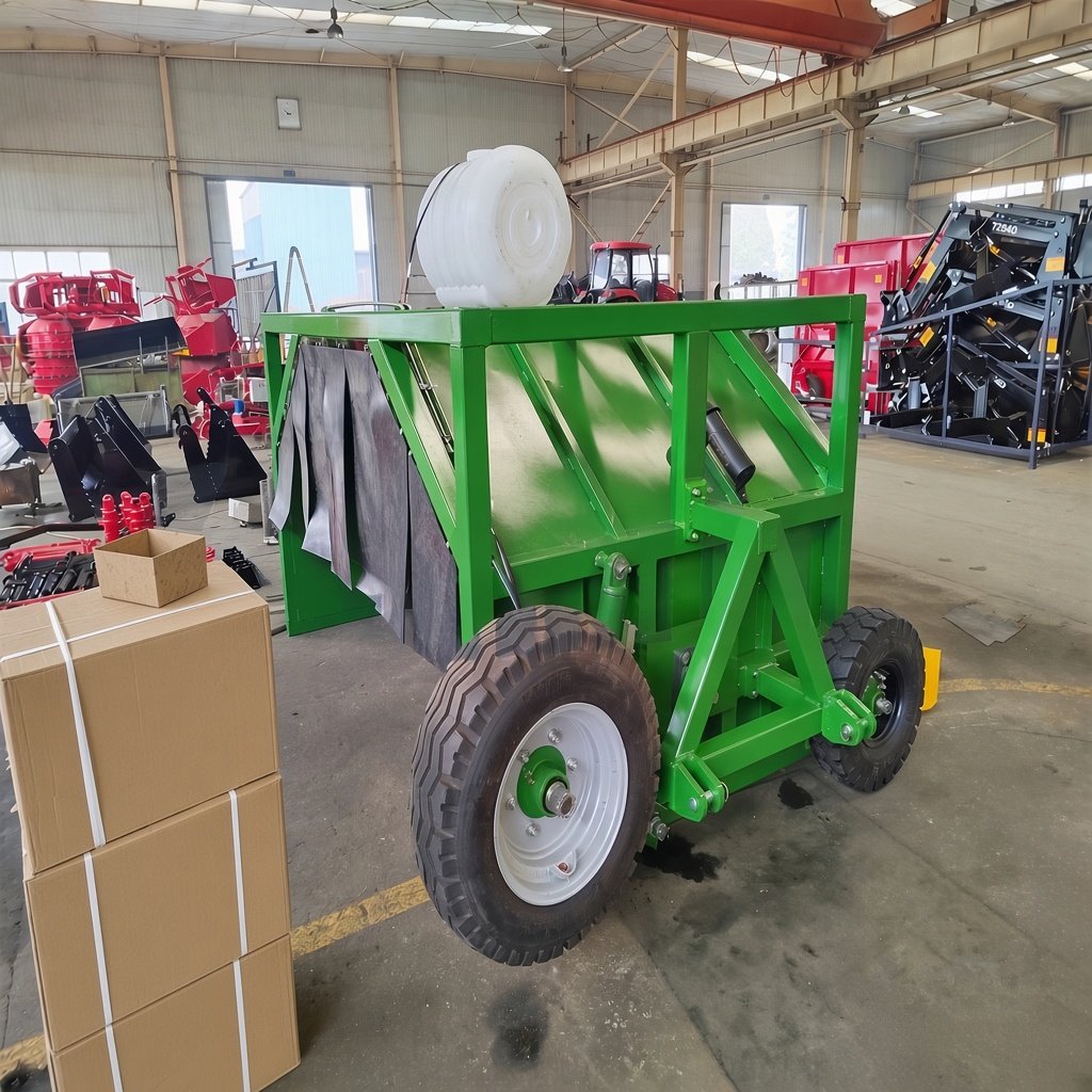 Green pull-type compost windrow turner seen from the rear, showing the hopper, flail curtain and water tank
